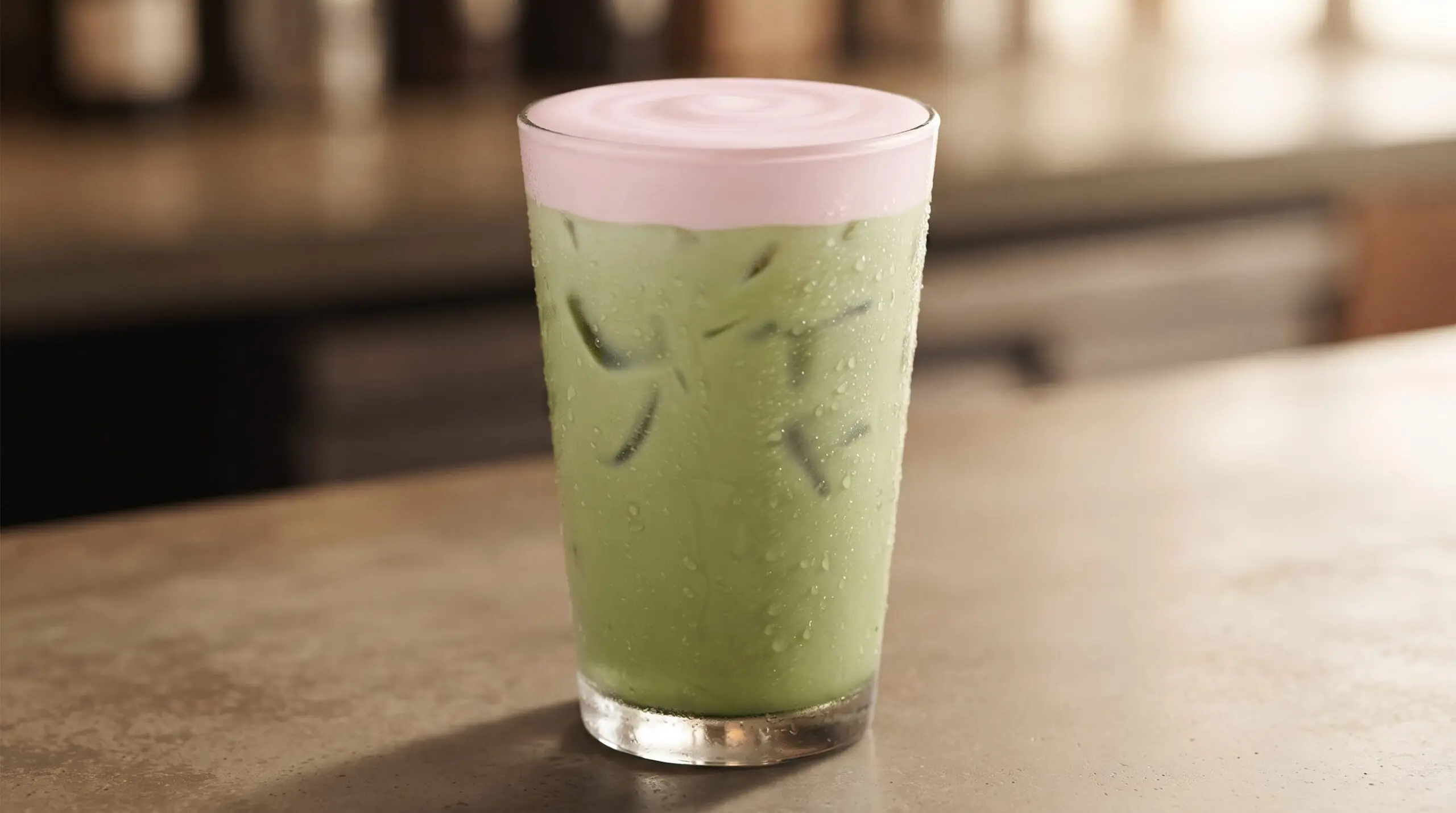 Tim Hortons Strawberry Iced Matcha Latte in a tall glass with ice and pink foam top.